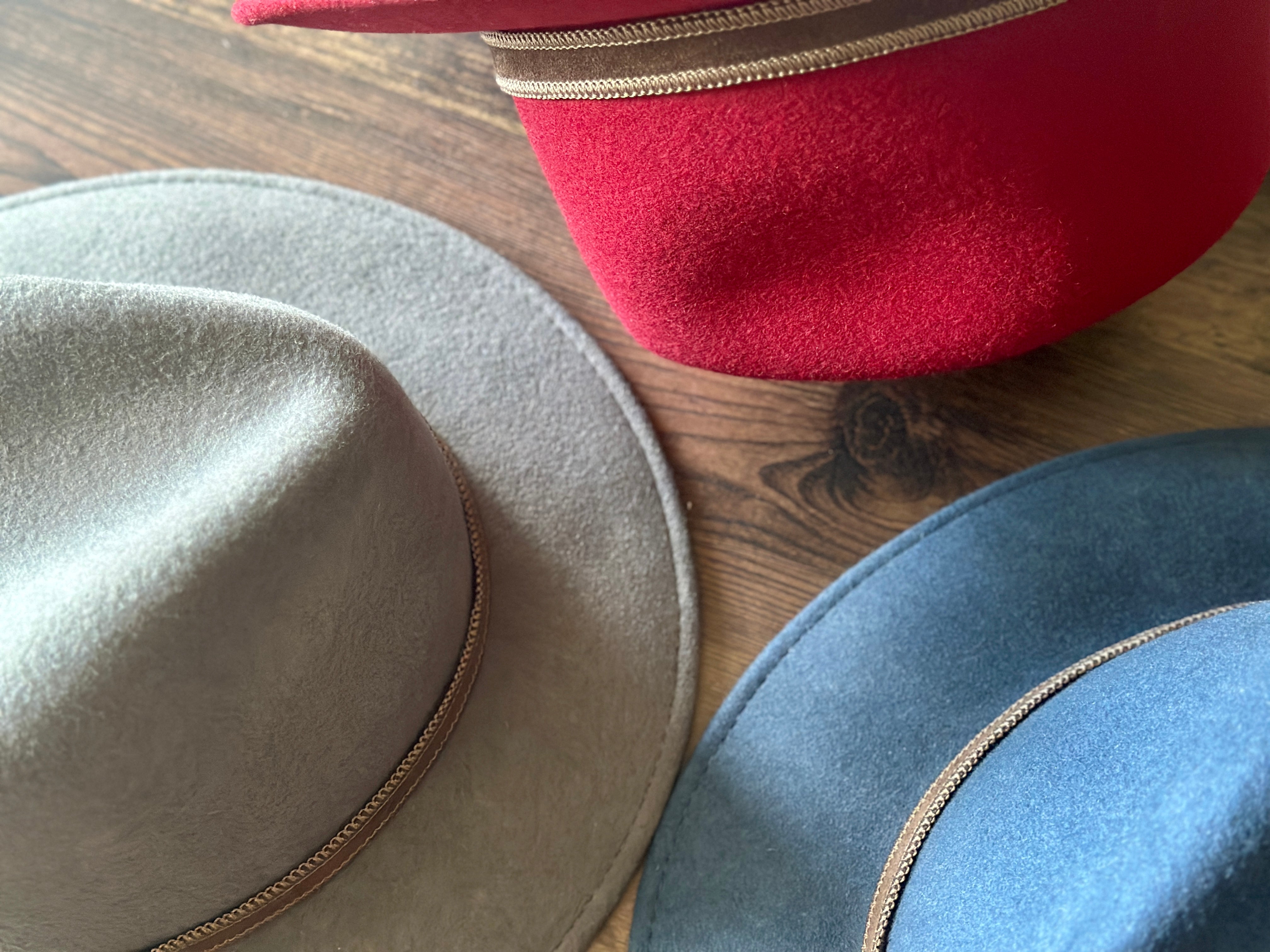 red, grey, and blue hats on wood table