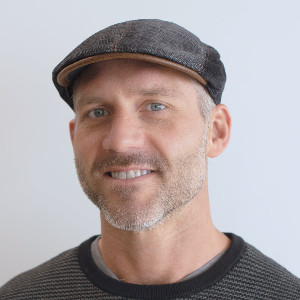 man wearing denim color corduroy cap with brown leather trim and stitching