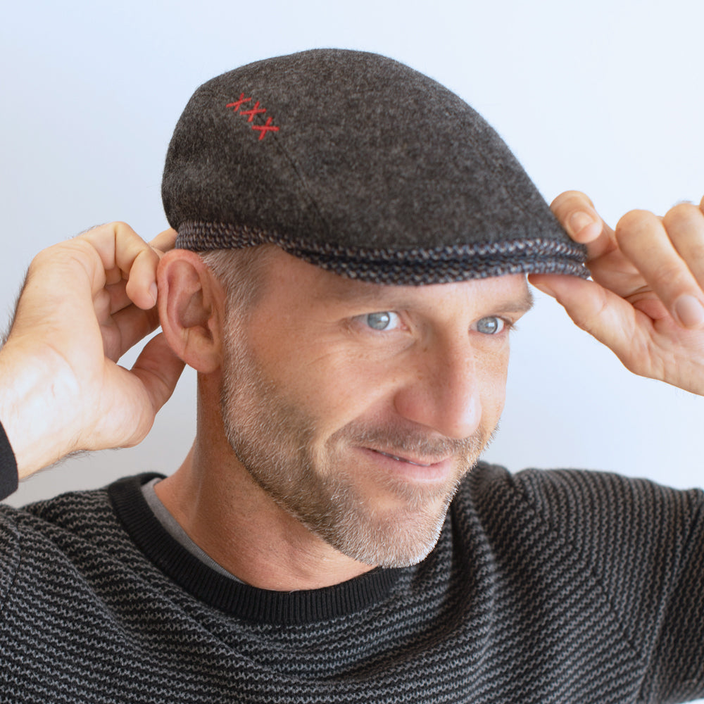 man wear charcoal and black ivy cap with contrasting trim and brim with xxx on side