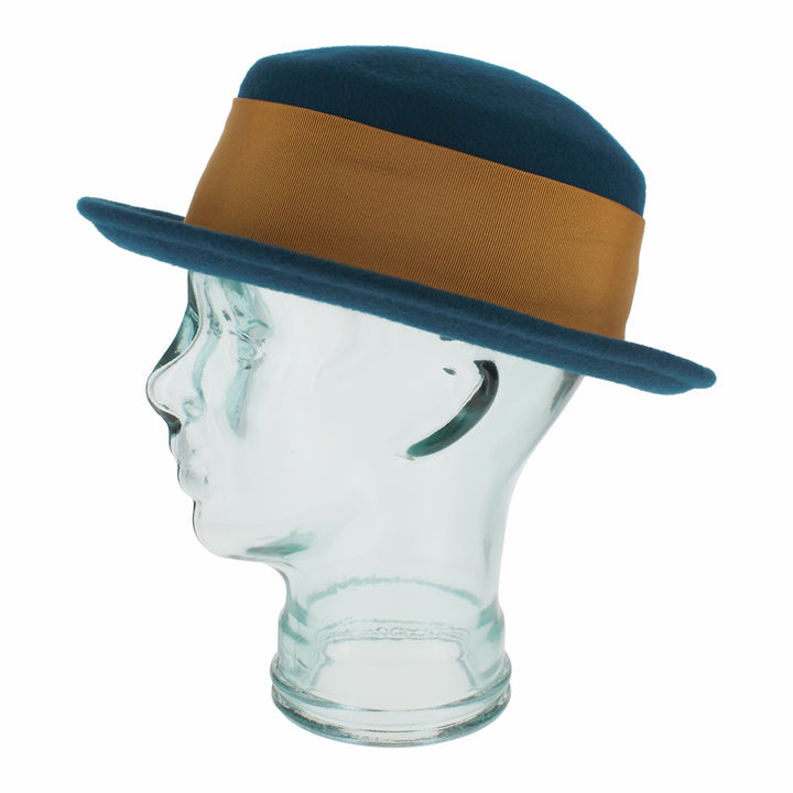 Angled view of the Belfry Gardiner teal blue boater in wool with grosgrain band and metallic bow accent, a luxurious accessory blending classic elegance with fall/winter style