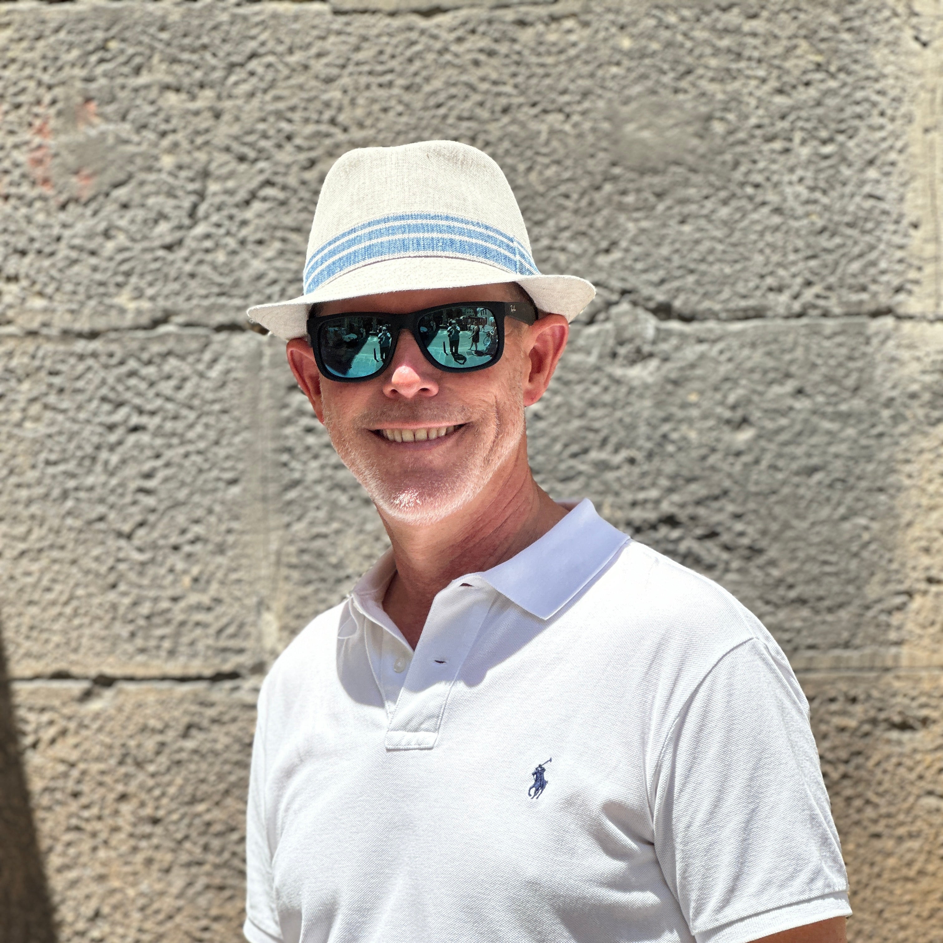 Lightweight natural linen trilby by Belfry Italia, featuring a blue-striped ribbon band, precise top-stitched brim, and travel-ready design