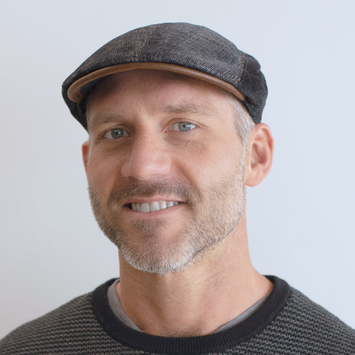 man wearing denim color corduroy cap with brown leather trim and stitching