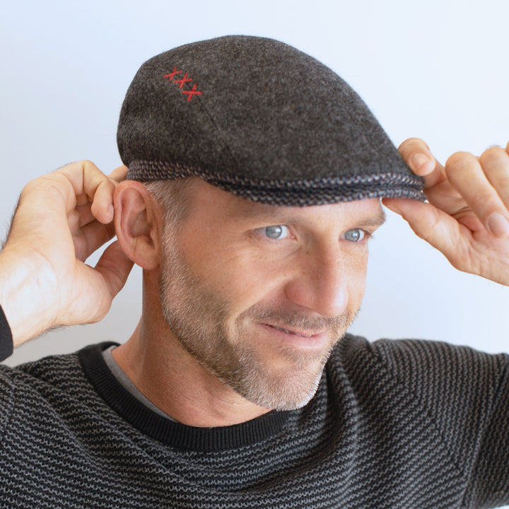 man wear charcoal and black ivy cap with contrasting trim and brim with xxx on side