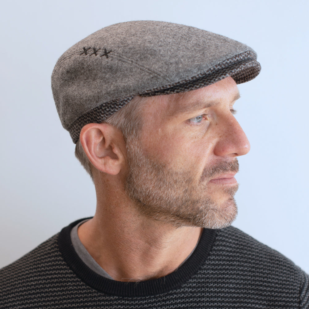 man wear light grey ivy cap with contrasting trim and brim with xxx on side