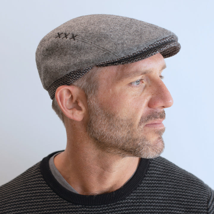man wear light grey ivy cap with contrasting trim and brim with xxx on side